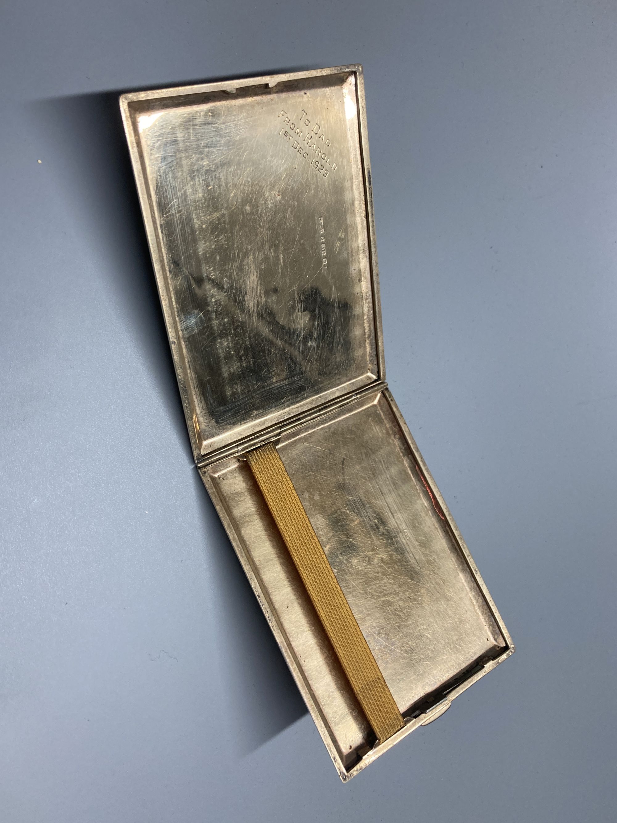 A late 1920s 9ct gold engine-turned cigarette case, with chased fleur-de-lys border, inscribed to interior, 11.3cm, gross 141g,